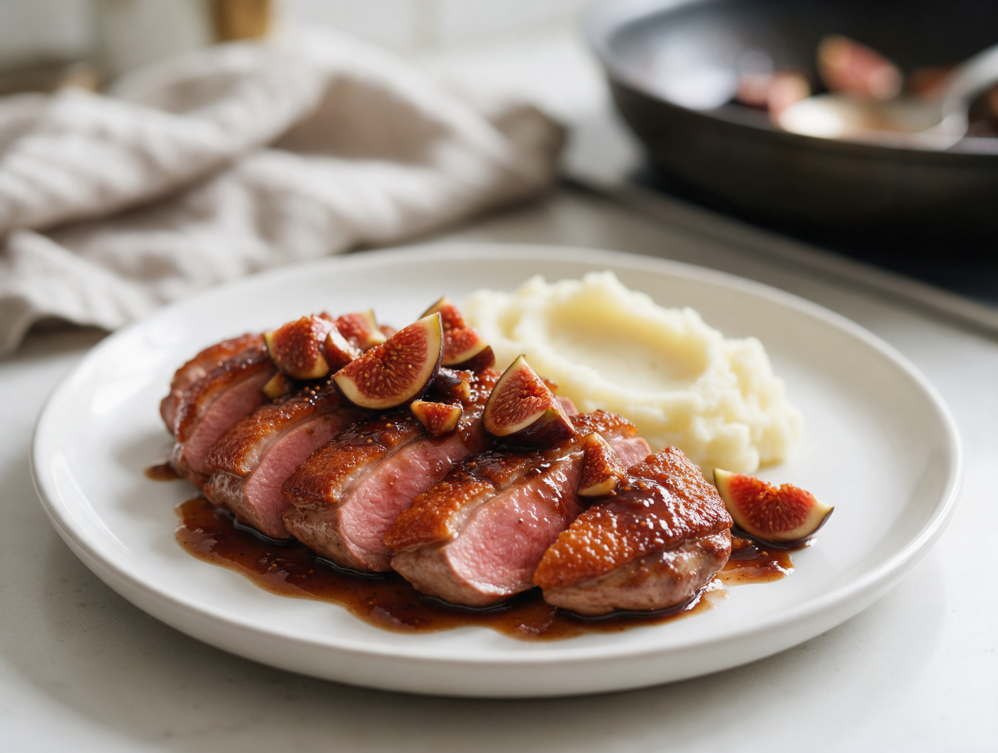 Sliced duck breast with crisp skin and glossy fresh fig glaze on a white plate